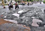 Corrugated trips forward: Moderate rain leaves the road ridden by a pothole