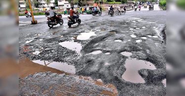 Corrugated trips forward: Moderate rain leaves the road ridden by a pothole