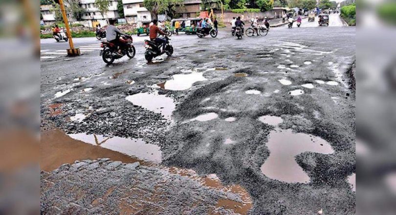 Corrugated trips forward: Moderate rain leaves the road ridden by a pothole